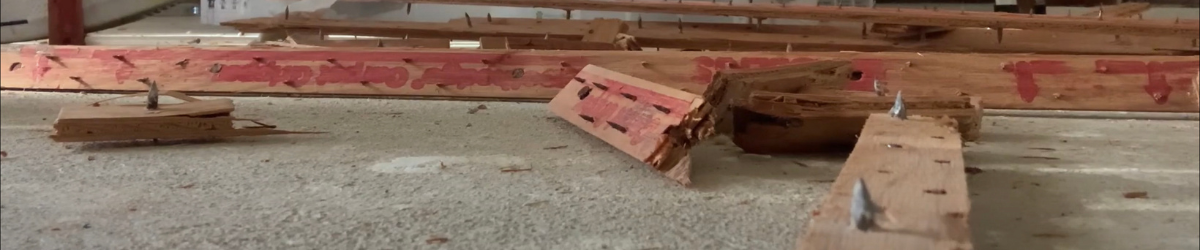 A pile of carpet tack strips is broken down by stepping on them individually.